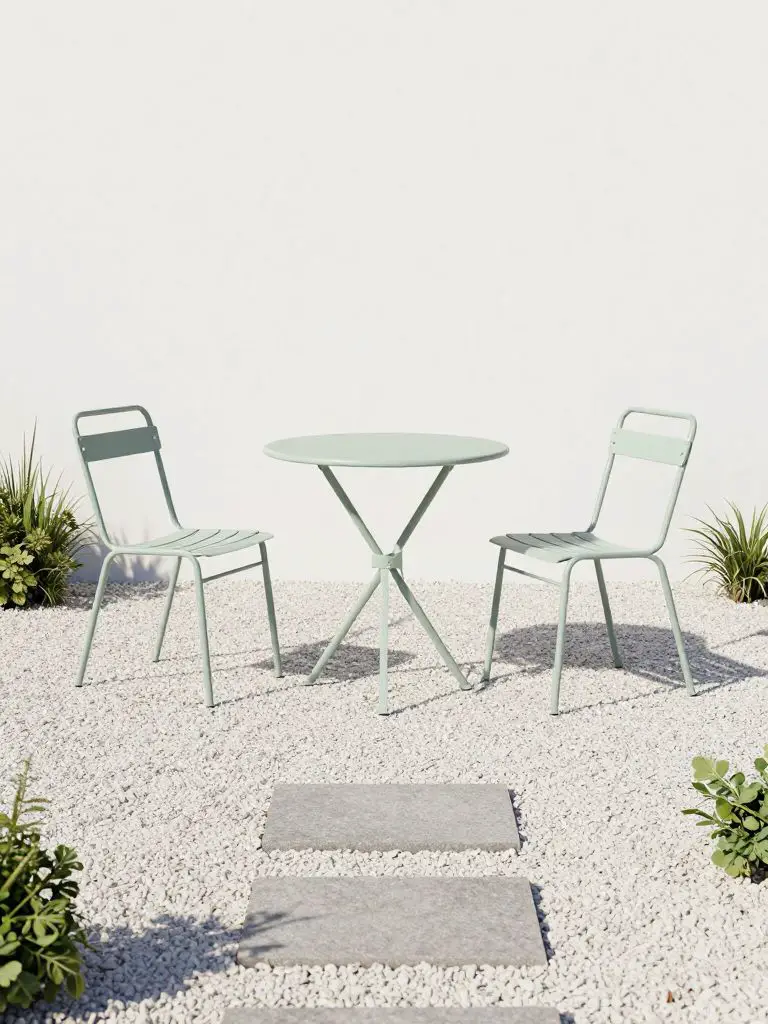 A minimal gravel patio in Scandinavian-inspired style featuring a small round bistro table and two lightweight chairs as the focal point.