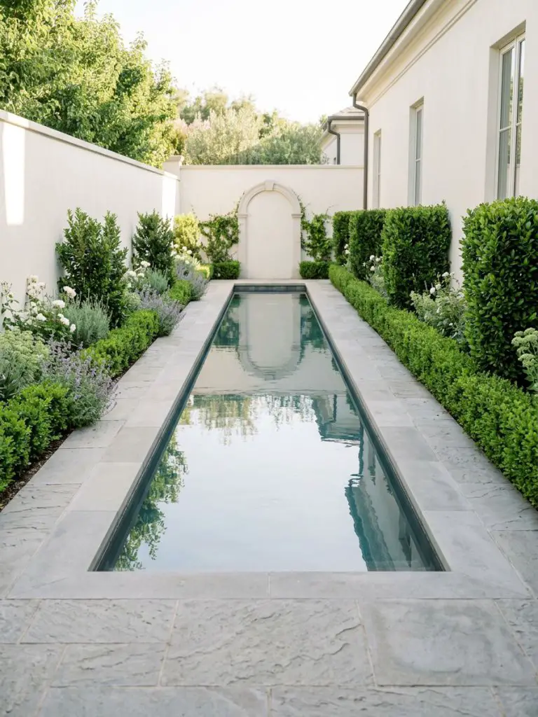A sleek side yard lap pool designed with symmetry and simplicity, featuring a long rectangular pool bordered by manicured hedges and a clean.
